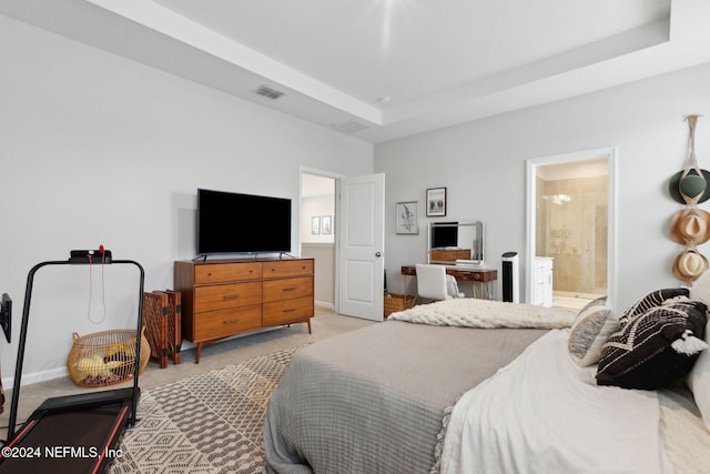 bedroom featuring ensuite bathroom, a tray ceiling, and light colored carpet