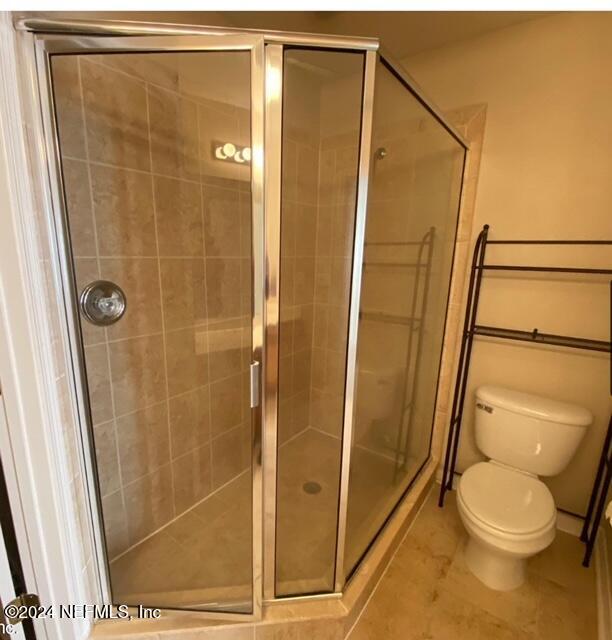 bathroom with tile patterned floors, toilet, and an enclosed shower