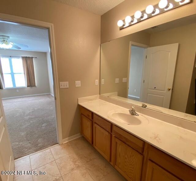 bathroom with tile patterned floors, vanity, ceiling fan, and a textured ceiling