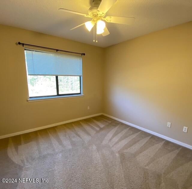 carpeted spare room featuring ceiling fan