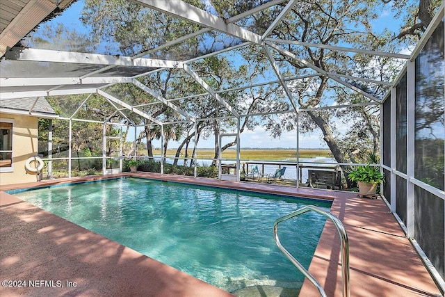 view of pool with glass enclosure, a patio area, and a water view