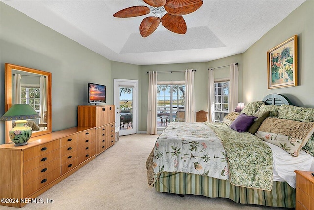 bedroom with access to outside, light colored carpet, multiple windows, and ceiling fan