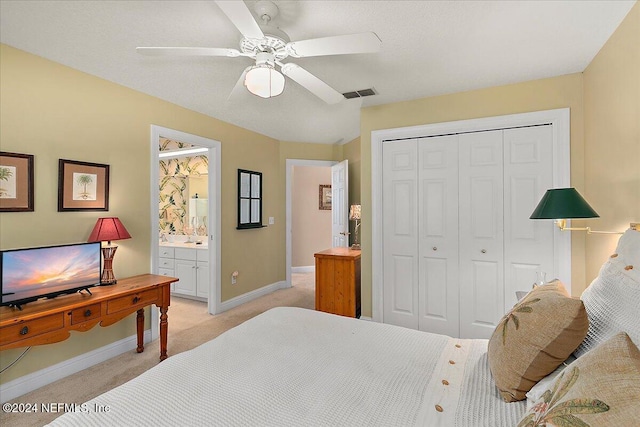 bedroom with ensuite bathroom, ceiling fan, a closet, and light colored carpet