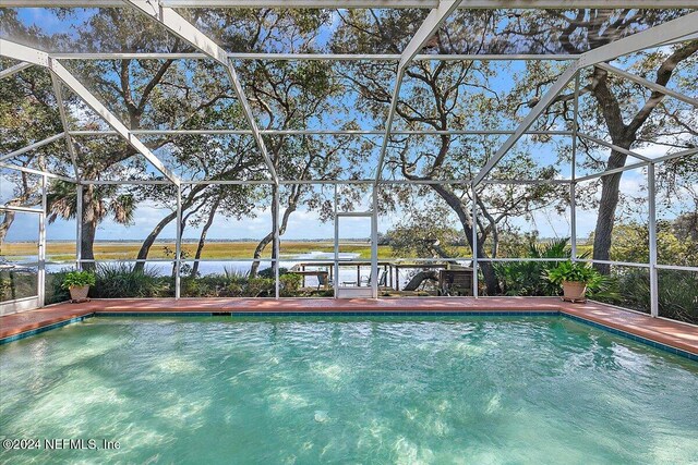 view of swimming pool with a lanai and a water view