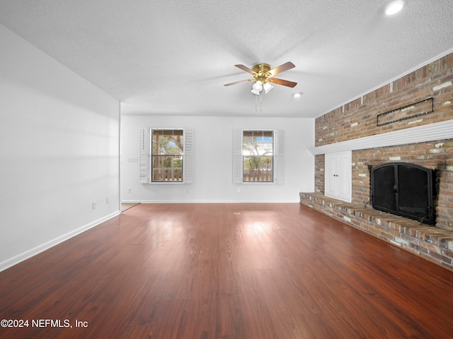 unfurnished living room with hardwood / wood-style floors, ceiling fan, a textured ceiling, and a brick fireplace