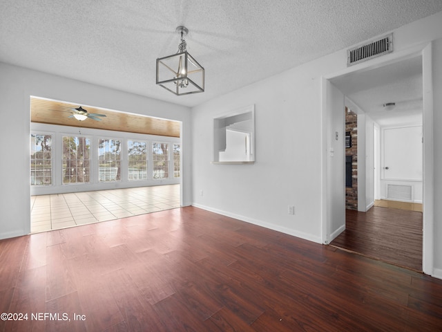 unfurnished living room with a textured ceiling, ceiling fan with notable chandelier, and hardwood / wood-style flooring