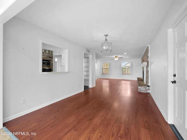 unfurnished living room featuring a fireplace, ceiling fan with notable chandelier, and wood-type flooring