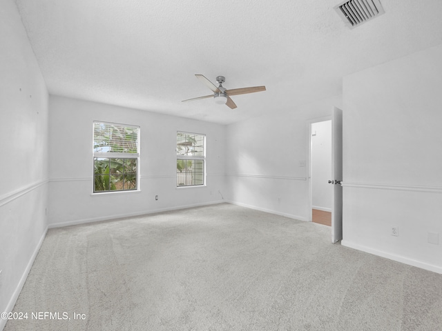 spare room featuring ceiling fan, a textured ceiling, and light carpet