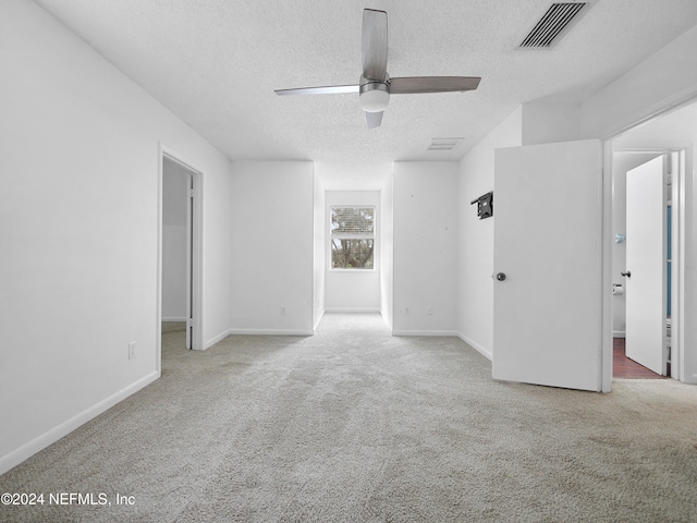 spare room featuring a textured ceiling, carpet floors, and ceiling fan