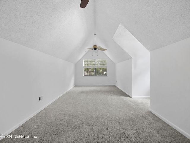 bonus room featuring a textured ceiling, light colored carpet, ceiling fan, and vaulted ceiling