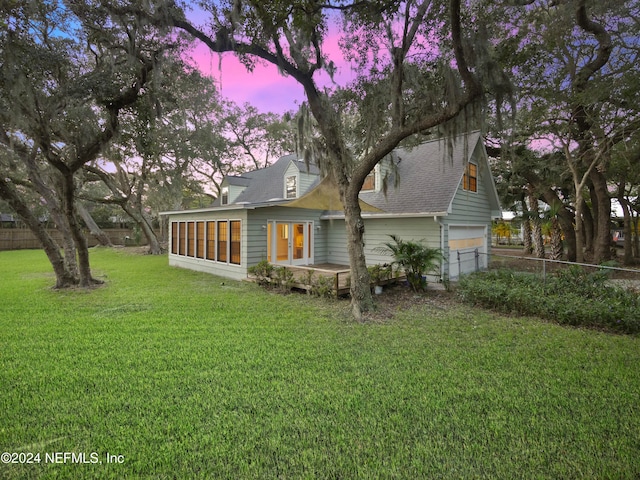 back house at dusk with a garage and a yard