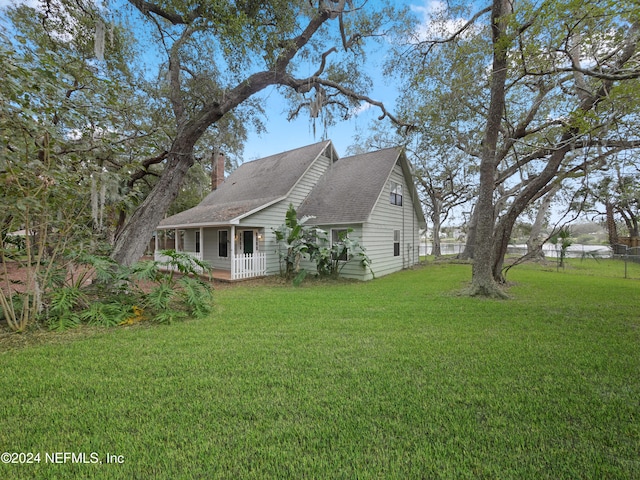 view of side of property featuring covered porch and a yard