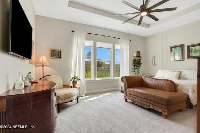 carpeted bedroom with a tray ceiling and ceiling fan