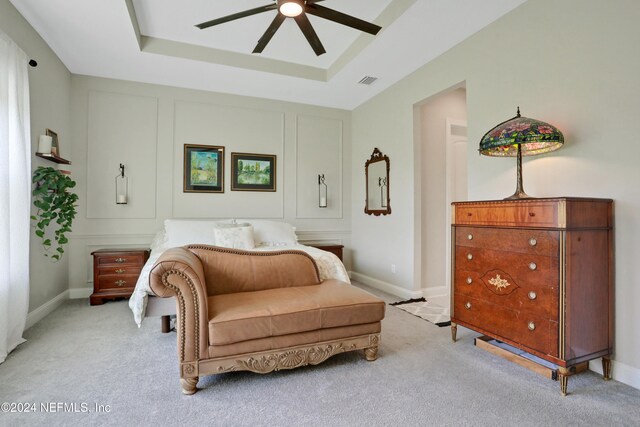 sitting room with light carpet, a tray ceiling, and ceiling fan