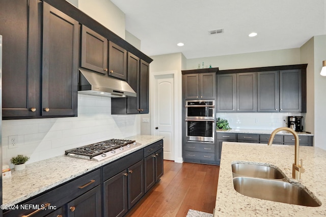 kitchen featuring backsplash, light stone countertops, sink, and dark wood-type flooring