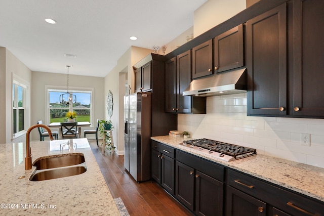 kitchen with light stone countertops, sink, hanging light fixtures, stainless steel gas cooktop, and dark brown cabinets