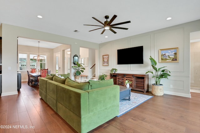 living room featuring ceiling fan with notable chandelier and hardwood / wood-style flooring