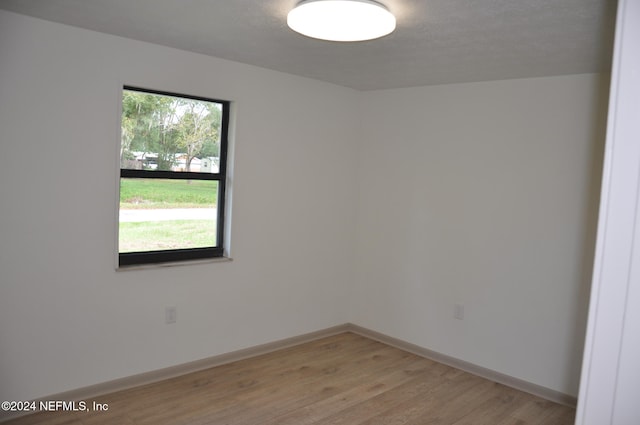 spare room with a textured ceiling and light hardwood / wood-style floors