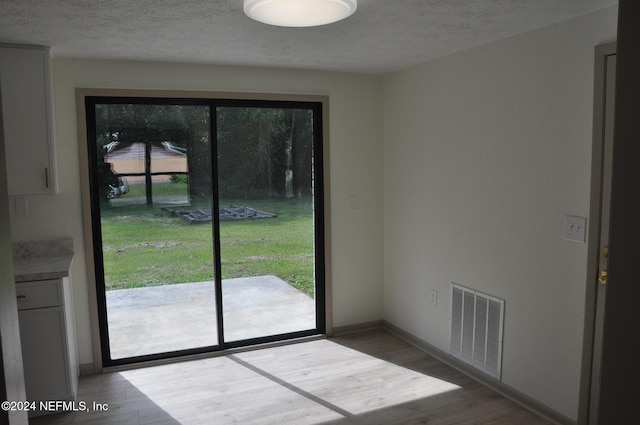 doorway to outside featuring a textured ceiling and light wood-type flooring