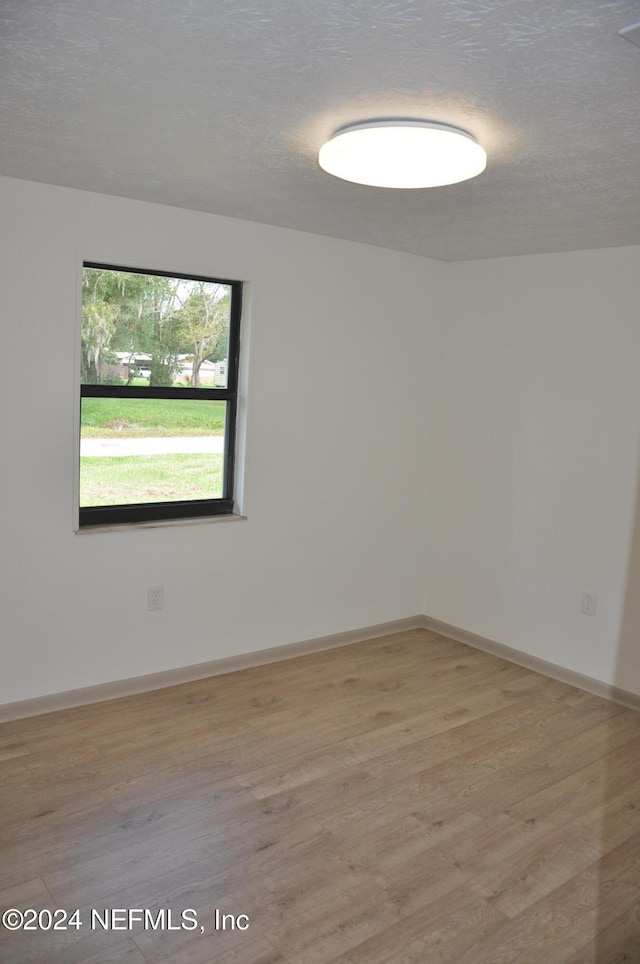 unfurnished room with a textured ceiling and light hardwood / wood-style flooring