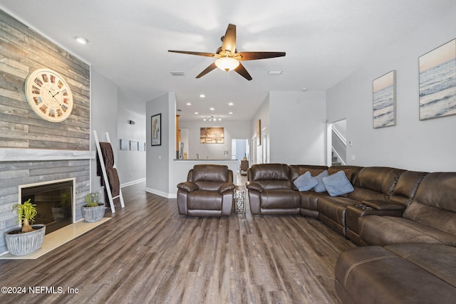 living room featuring a large fireplace, dark hardwood / wood-style floors, and ceiling fan