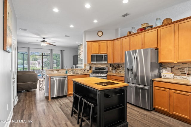 kitchen featuring a breakfast bar, a kitchen island, wood-type flooring, and appliances with stainless steel finishes