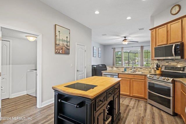 kitchen with a center island, sink, decorative backsplash, appliances with stainless steel finishes, and wood-type flooring