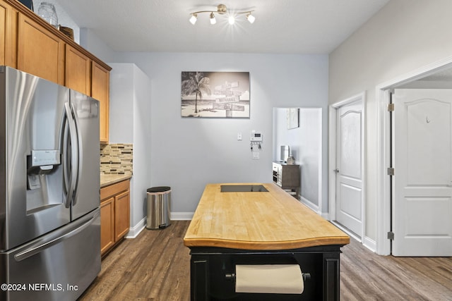 kitchen with stainless steel fridge, backsplash, a textured ceiling, and dark wood-type flooring