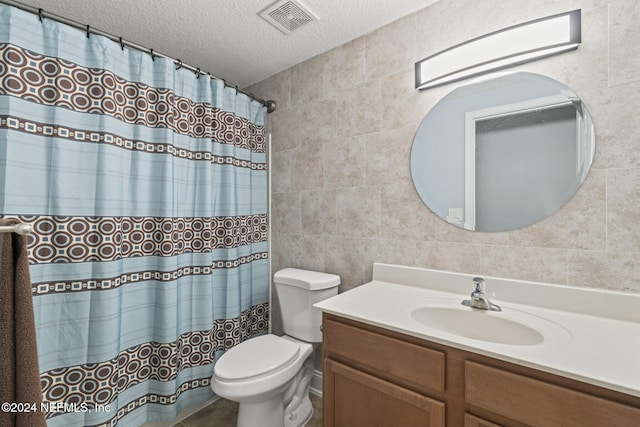 bathroom with a shower with curtain, a textured ceiling, toilet, vanity, and tile walls