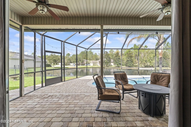 sunroom / solarium with ceiling fan, a water view, and a healthy amount of sunlight