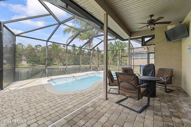 view of swimming pool with a lanai, ceiling fan, a water view, and a patio