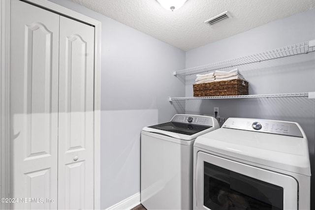 washroom with a textured ceiling and separate washer and dryer