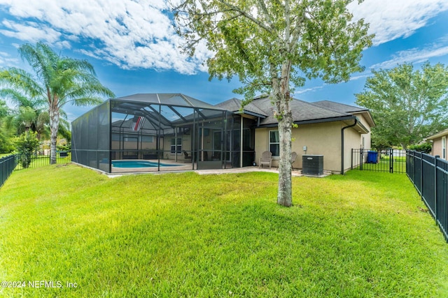 back of property with central air condition unit, glass enclosure, a lawn, and a fenced in pool