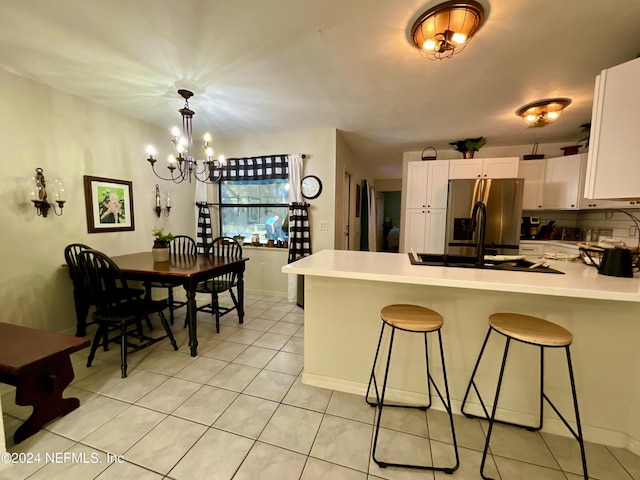 kitchen featuring stainless steel refrigerator with ice dispenser, sink, a notable chandelier, white cabinetry, and light tile patterned flooring