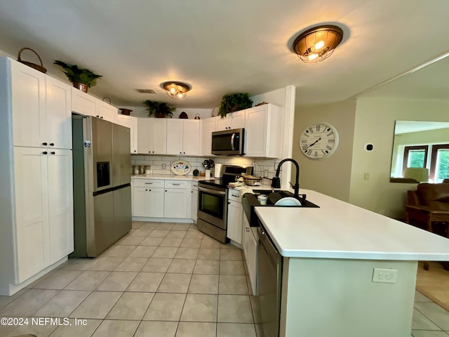 kitchen with sink, stainless steel appliances, white cabinets, backsplash, and light tile patterned flooring