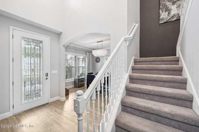 stairway with hardwood / wood-style flooring and a chandelier