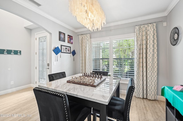 dining area featuring an inviting chandelier, crown molding, and light hardwood / wood-style flooring