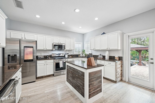 kitchen featuring white cabinets, appliances with stainless steel finishes, light hardwood / wood-style flooring, and a wealth of natural light