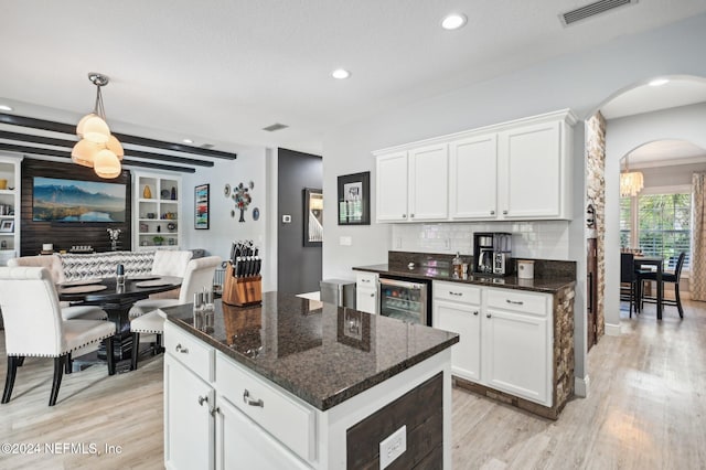 kitchen with wine cooler, white cabinetry, a kitchen island, and dark stone counters