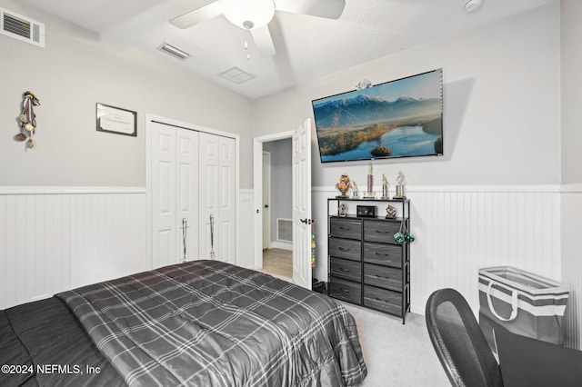 bedroom with ceiling fan, light colored carpet, a textured ceiling, and a closet