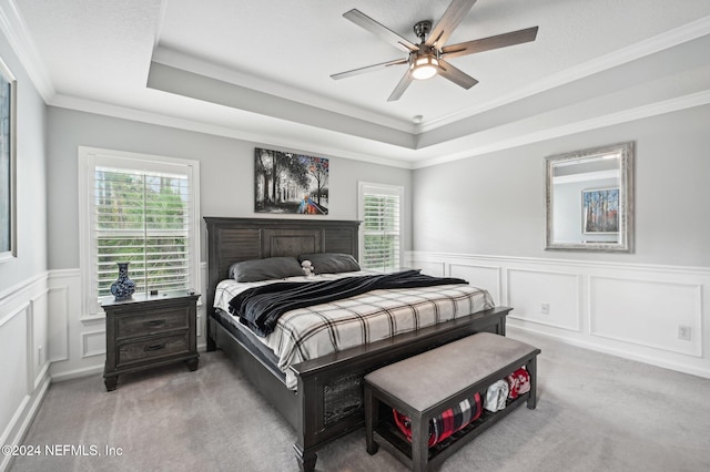 carpeted bedroom featuring a tray ceiling, ceiling fan, and ornamental molding