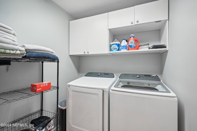 clothes washing area with cabinets and washer and clothes dryer