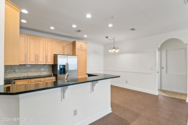 kitchen featuring light brown cabinets, stainless steel refrigerator with ice dispenser, backsplash, a chandelier, and decorative light fixtures