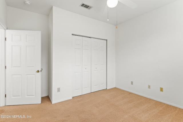 unfurnished bedroom featuring a closet, light colored carpet, and ceiling fan