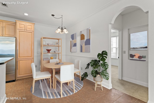 tiled dining room with crown molding and an inviting chandelier