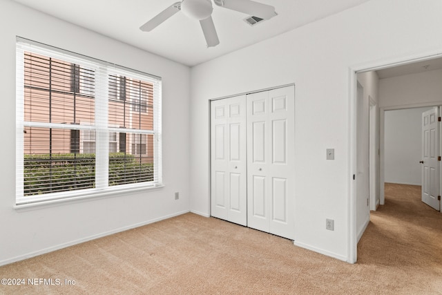 unfurnished bedroom featuring light carpet, a closet, and ceiling fan