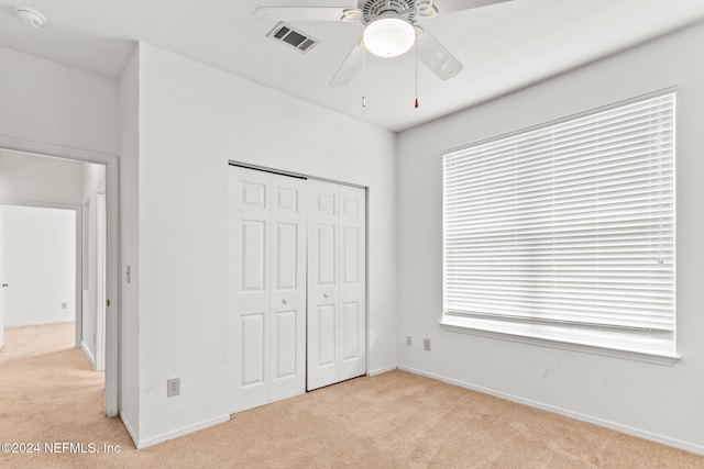 unfurnished bedroom with ceiling fan, light carpet, and a closet