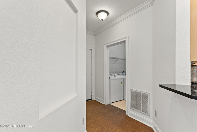 corridor with crown molding, dark tile patterned flooring, and independent washer and dryer