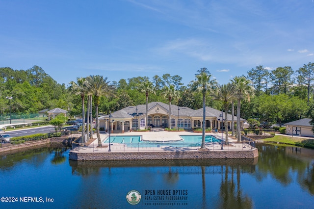 rear view of house with a community pool, a water view, and a patio