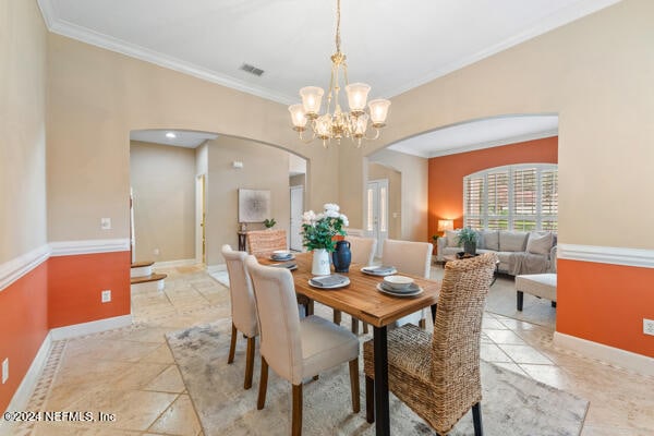 dining room with ornamental molding and a notable chandelier